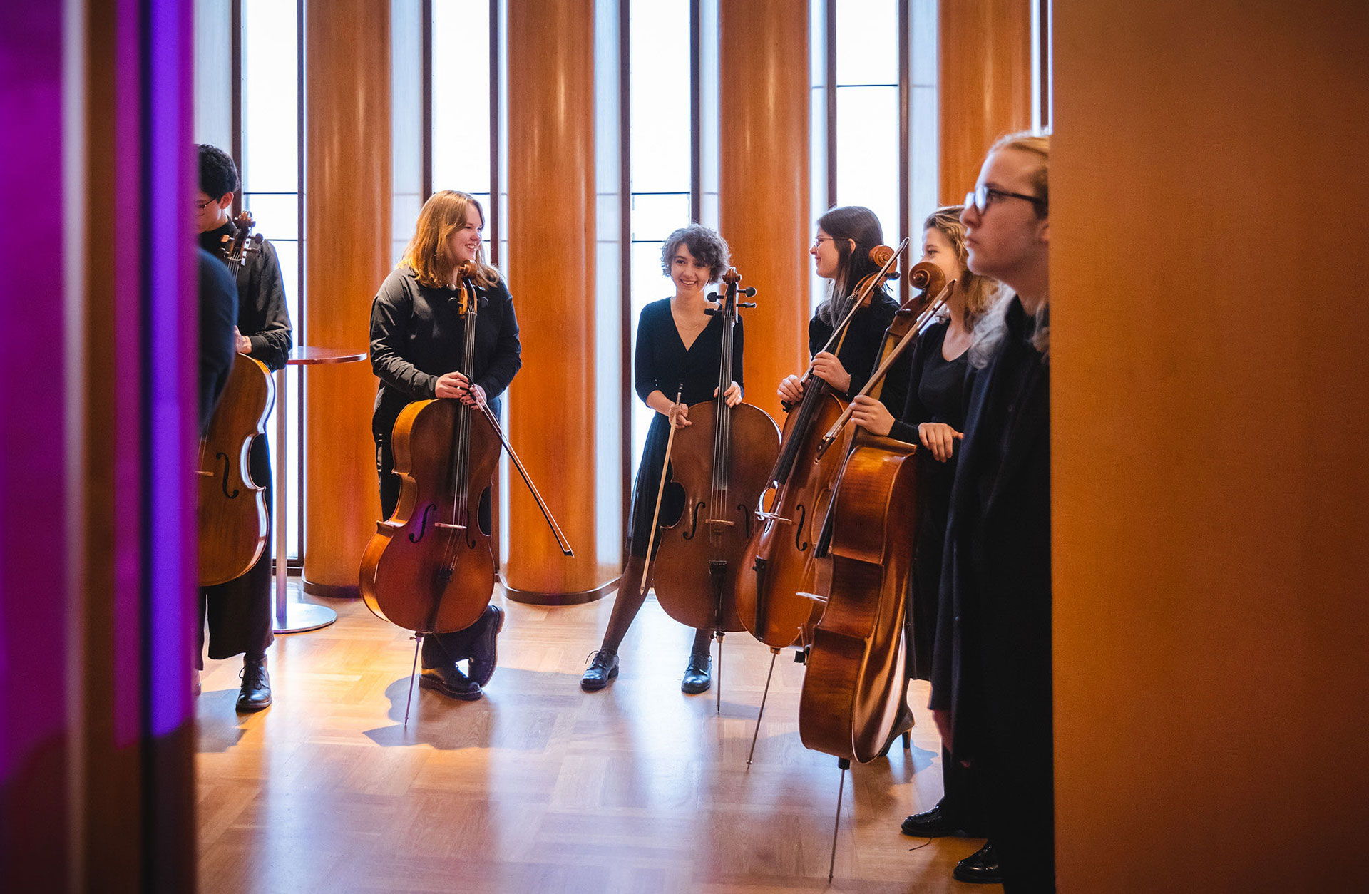 Glada ungdomar med cello i konserthusets foajé.