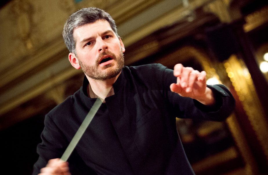 Dirigenten Johannes Gustavsson i intensiv dirigentpose med taktpinnen i handen.
