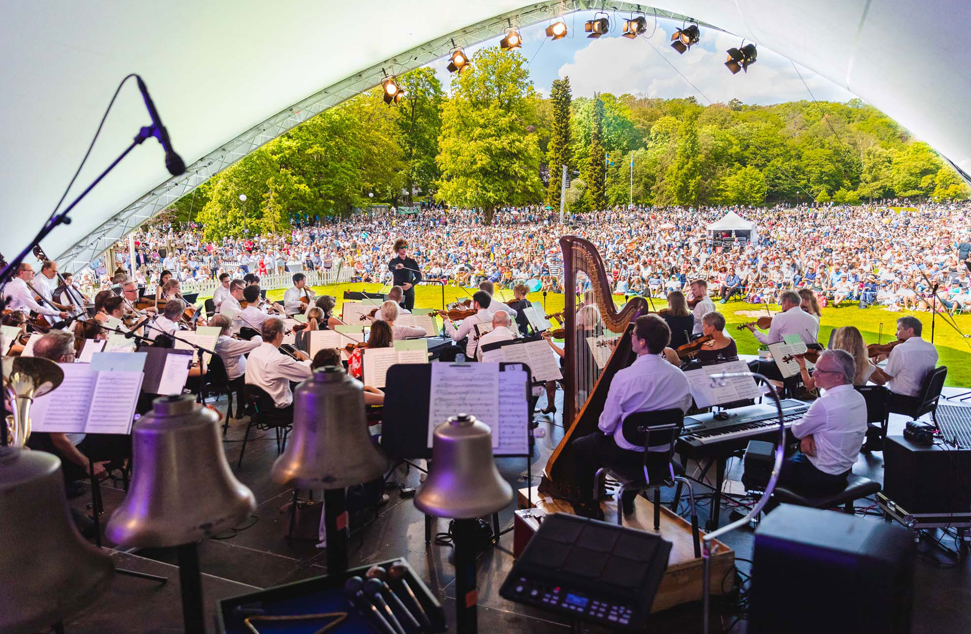 Orkestern på scenen med utsikt över det stora publikhavet en solig dag.