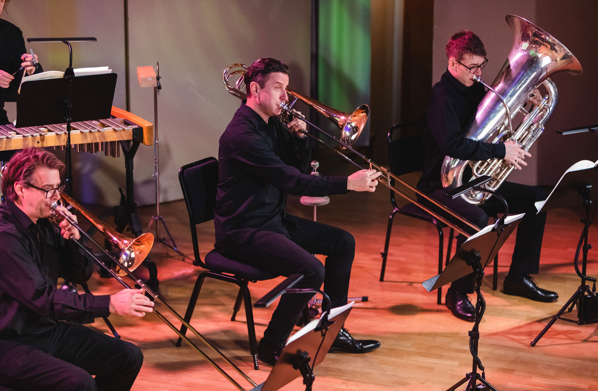 Två trombonister, en tuabist och en slagverkare i bakgrunden.