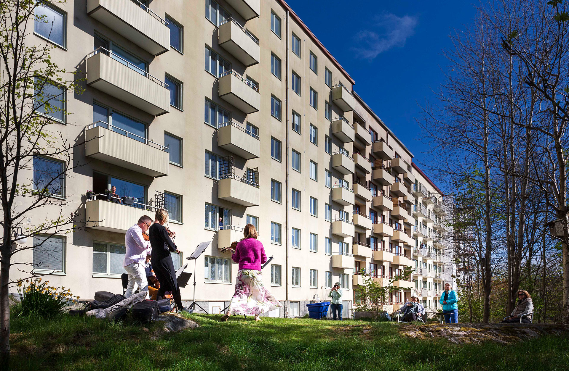 En kvartett från Göteborgs Symfoniker spelar utanför ett höghus. Människor lyssnar från fönstren och står runt om på gården.