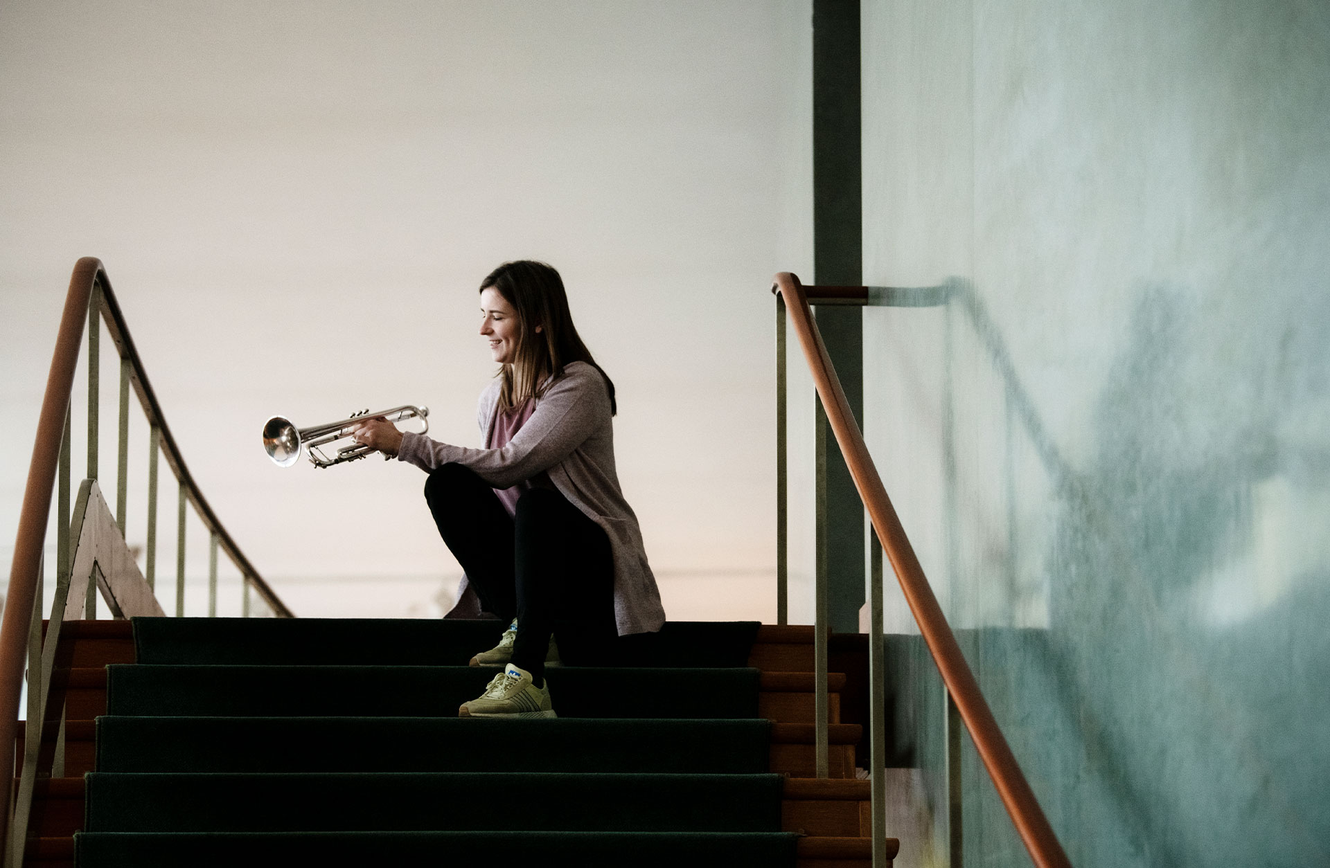 Urška Kurbos sitter i en trappa med sin trumpet.