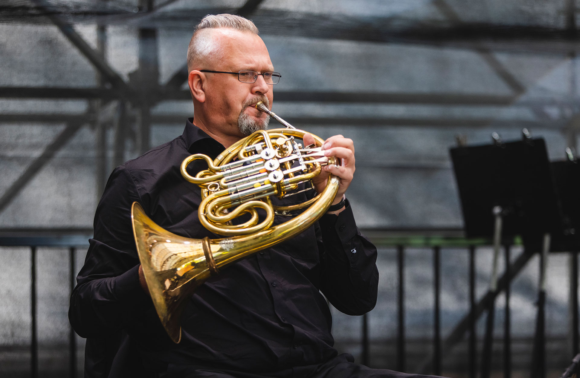 Dick spelar horn vid en konsert utomhus.