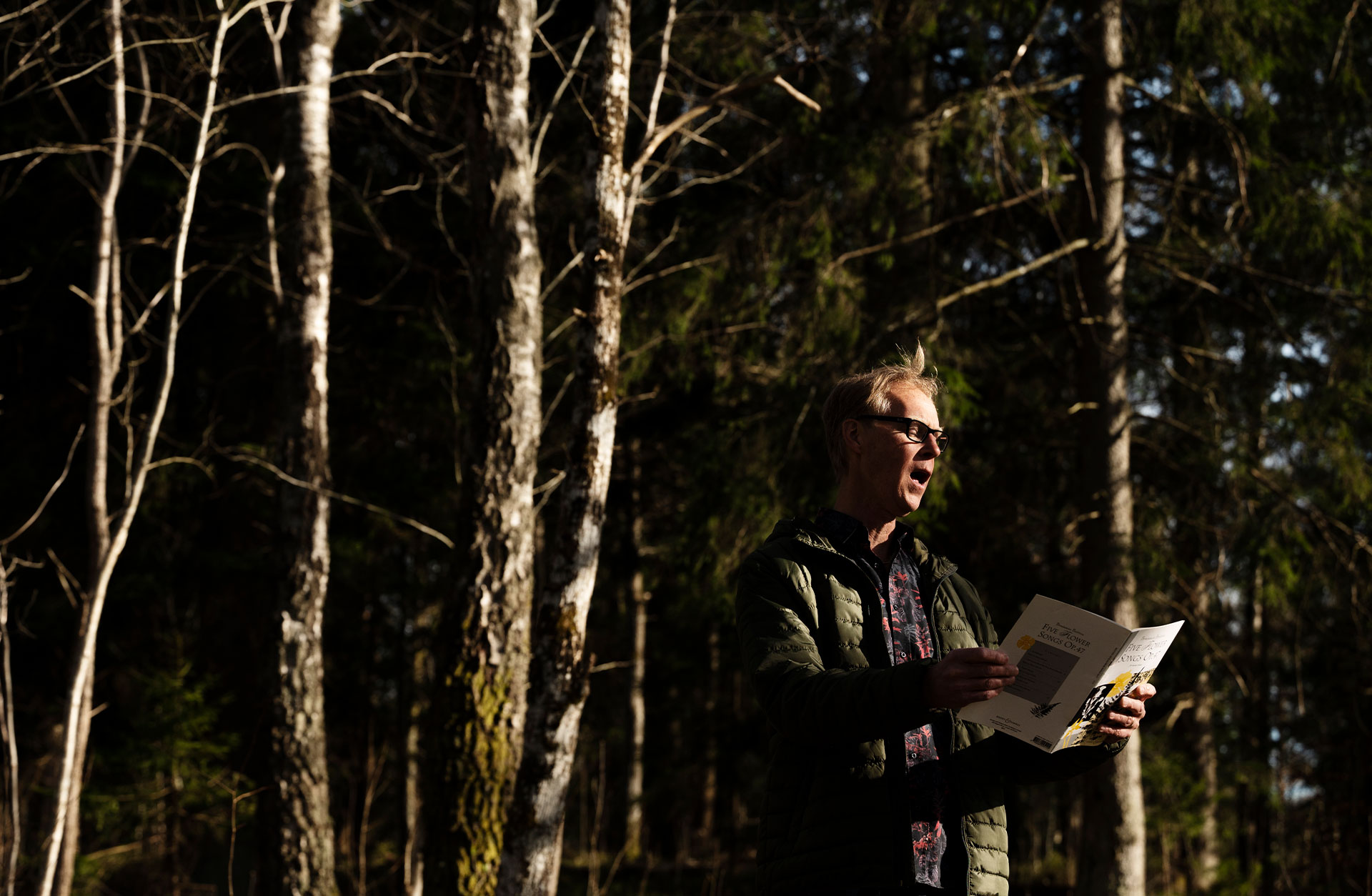 Ture står och håller ett sånghäfte och sjunger ut i skogen