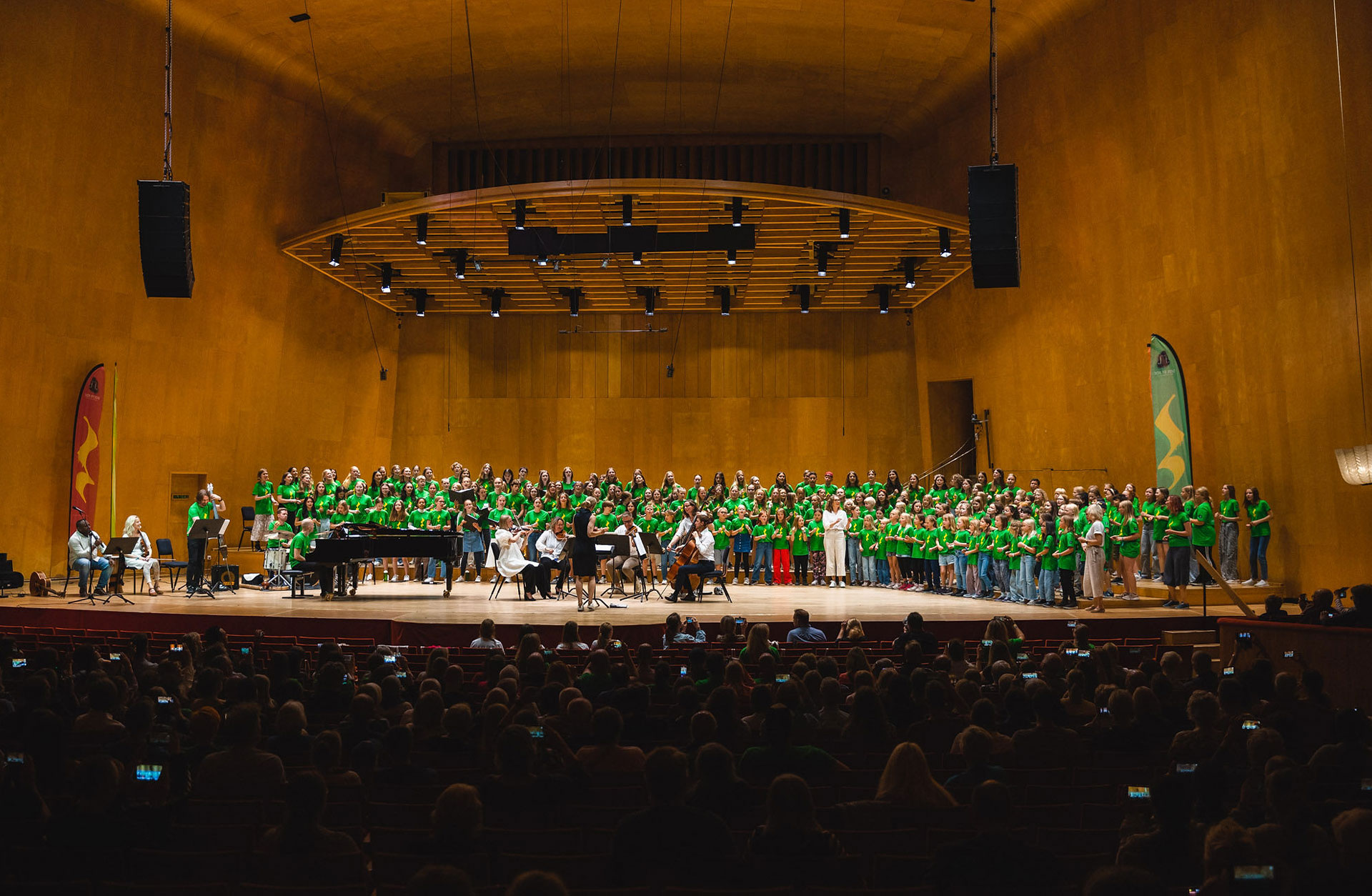 ungdomar som sjunger på stora scenen tillsammans med en liten orkester