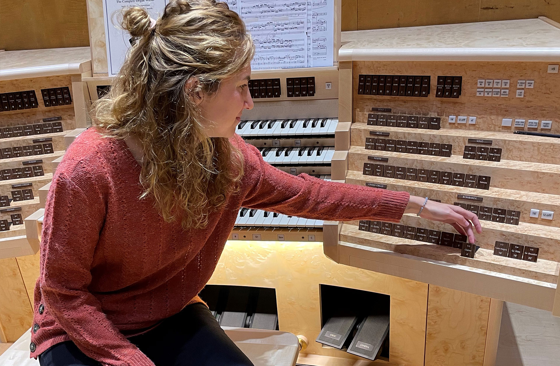 Ana Benedicic, sitter vid Konserthusorgelns spelbord. Hon visar en av knapparna på spelbordet..