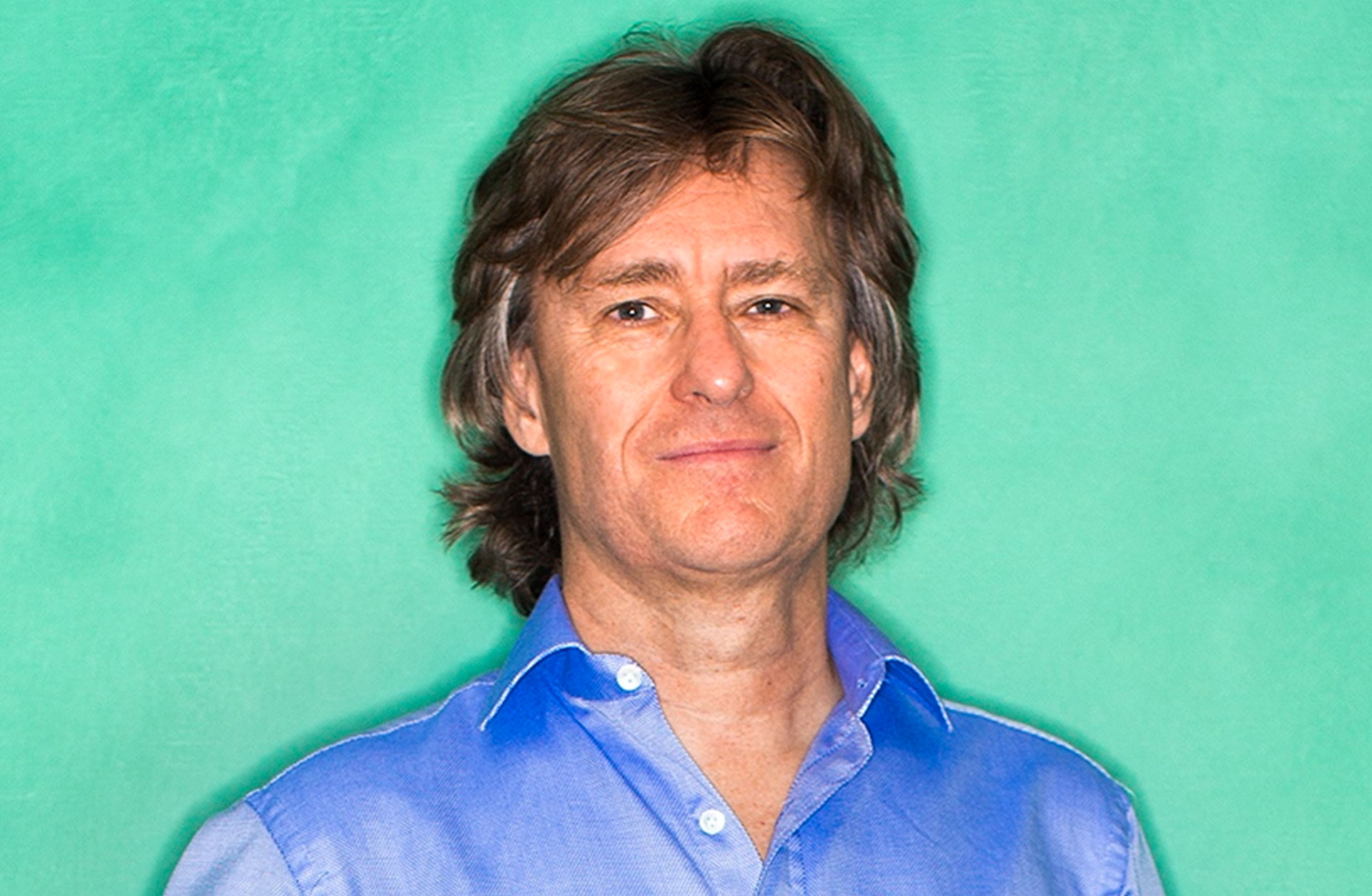Anders Hillborg, klädd i blå skjorta framför en grön vägg.