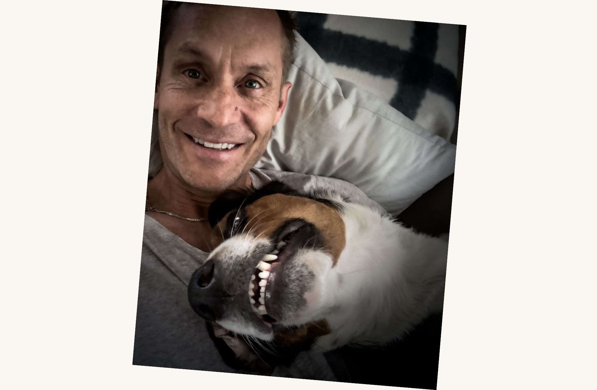 En glad Joakim med hunden Tully i knät. De sitter i en soffa.