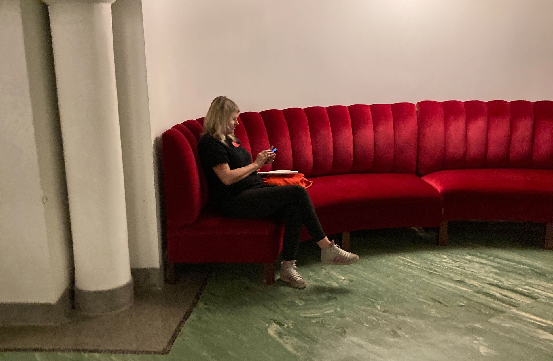 En podietekniker sitter i en röd sammatssoffa och tar igen sig.