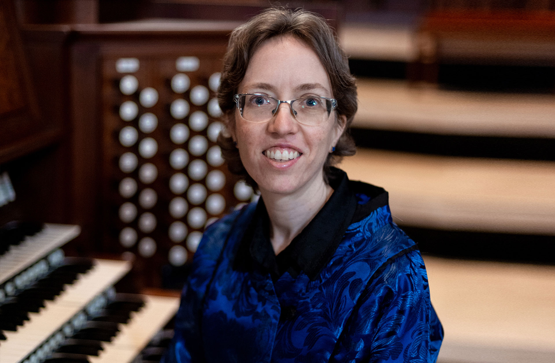 Kvinna i blå blus framför en orgel.