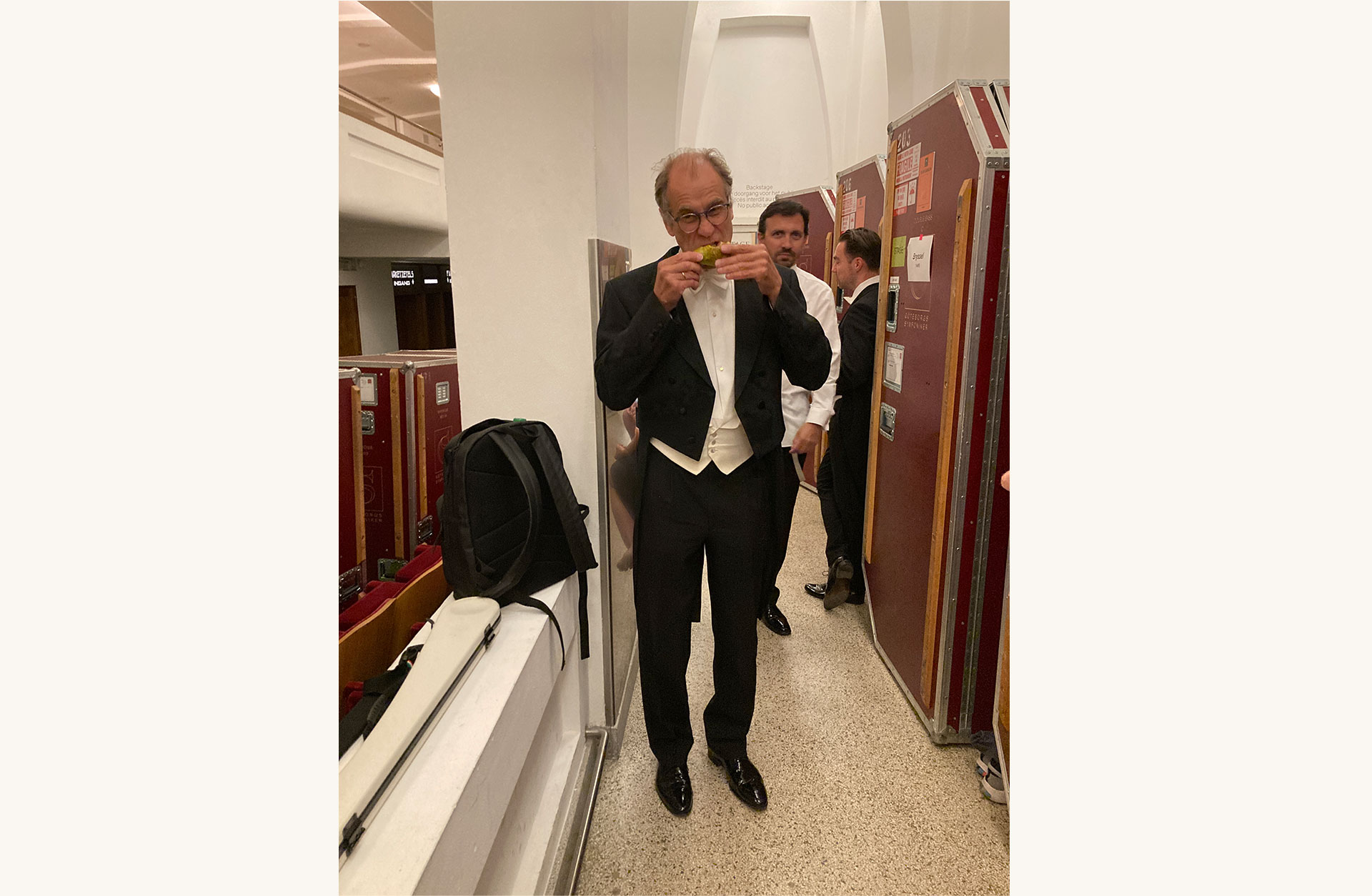 Jan Alm iklädd frack, ätandes på ett päron.