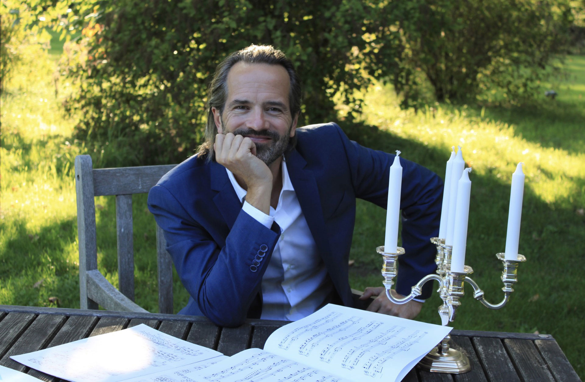 Peter Jablonski sitter vid ett bord i en soldränkt trädgård.