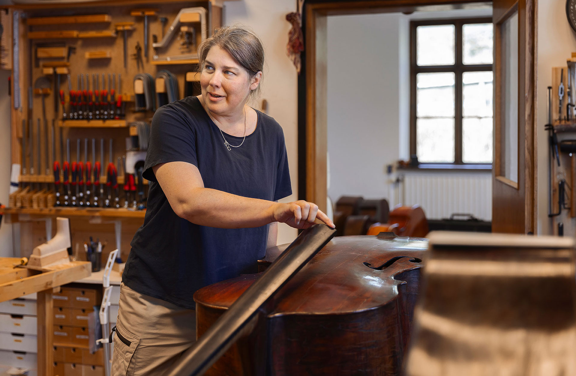 Elinor Morris arbetar med en kontrabas i sin verkstad.