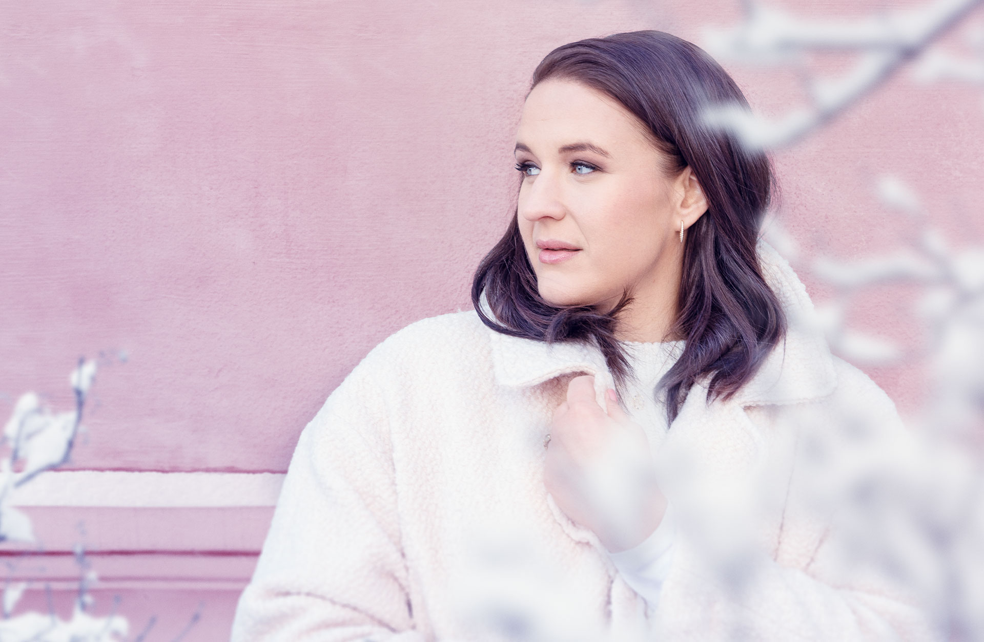 Lise Davidsen i vit jacka mot en rosa vägg.