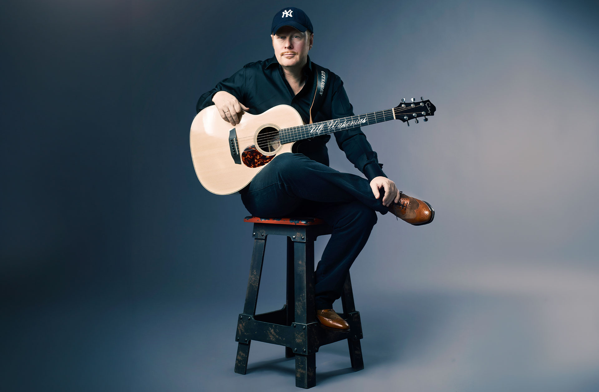 Sittande porträtt av Ulf Wakenius med sin gitarr.