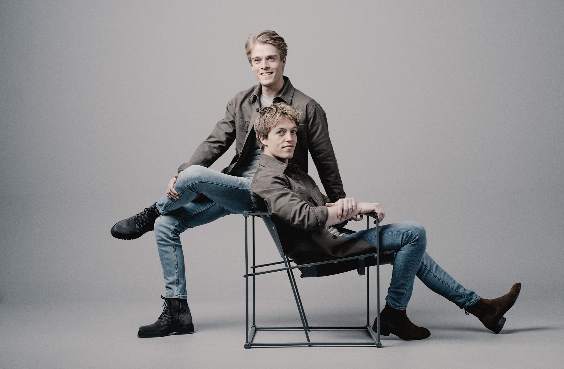 Två unga killar, Lucas och Arthur, sitter i olika positioner på var sin stol. De är ledigt klädda.