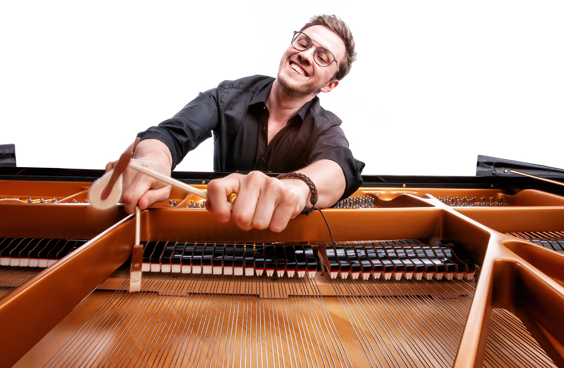 Glad pianist spelar på strängarna inne i flygeln.