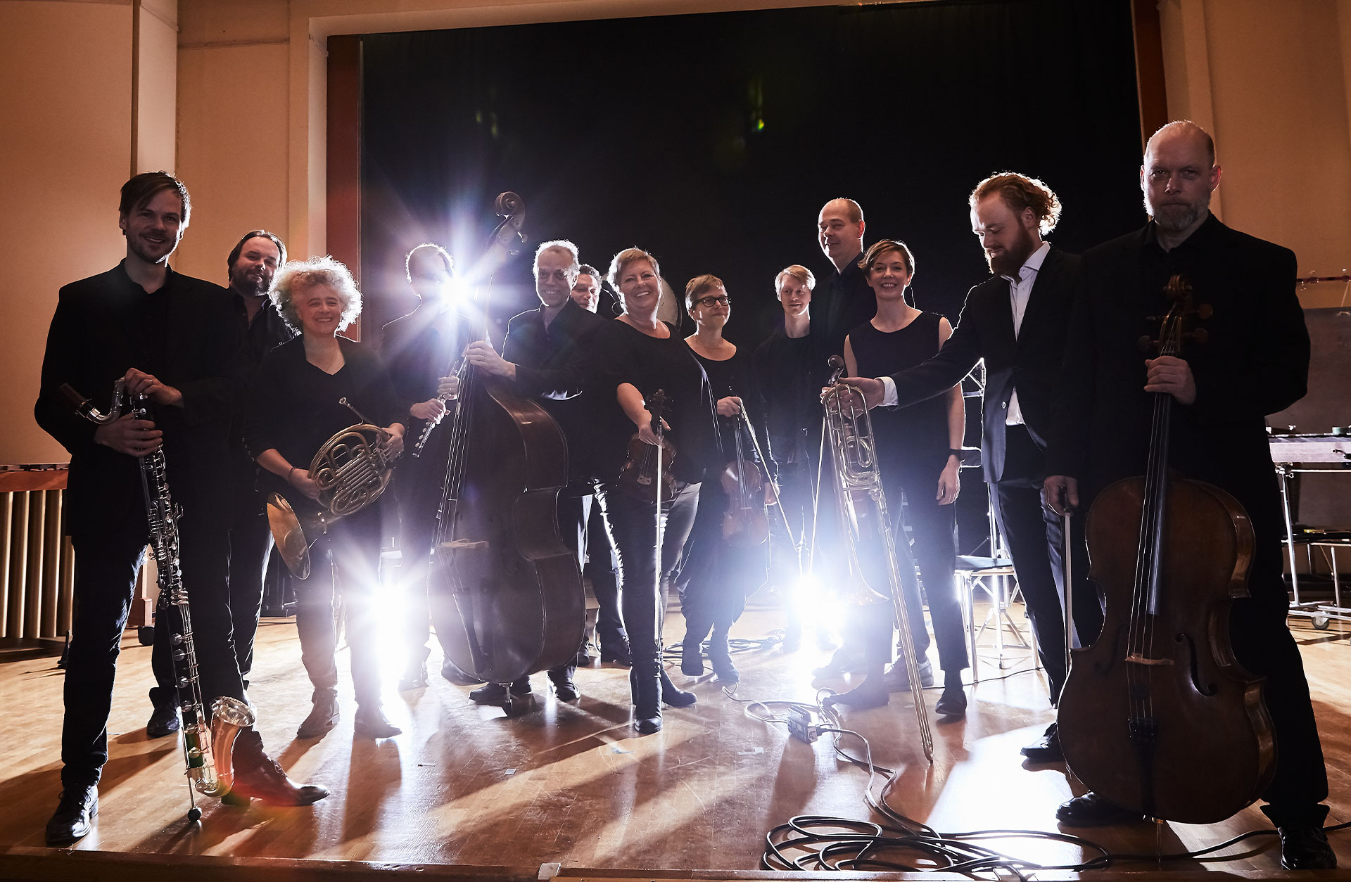 Ensamble med musiker står på rad framför kameran och lampor skapar motljuseffekt i bilden.