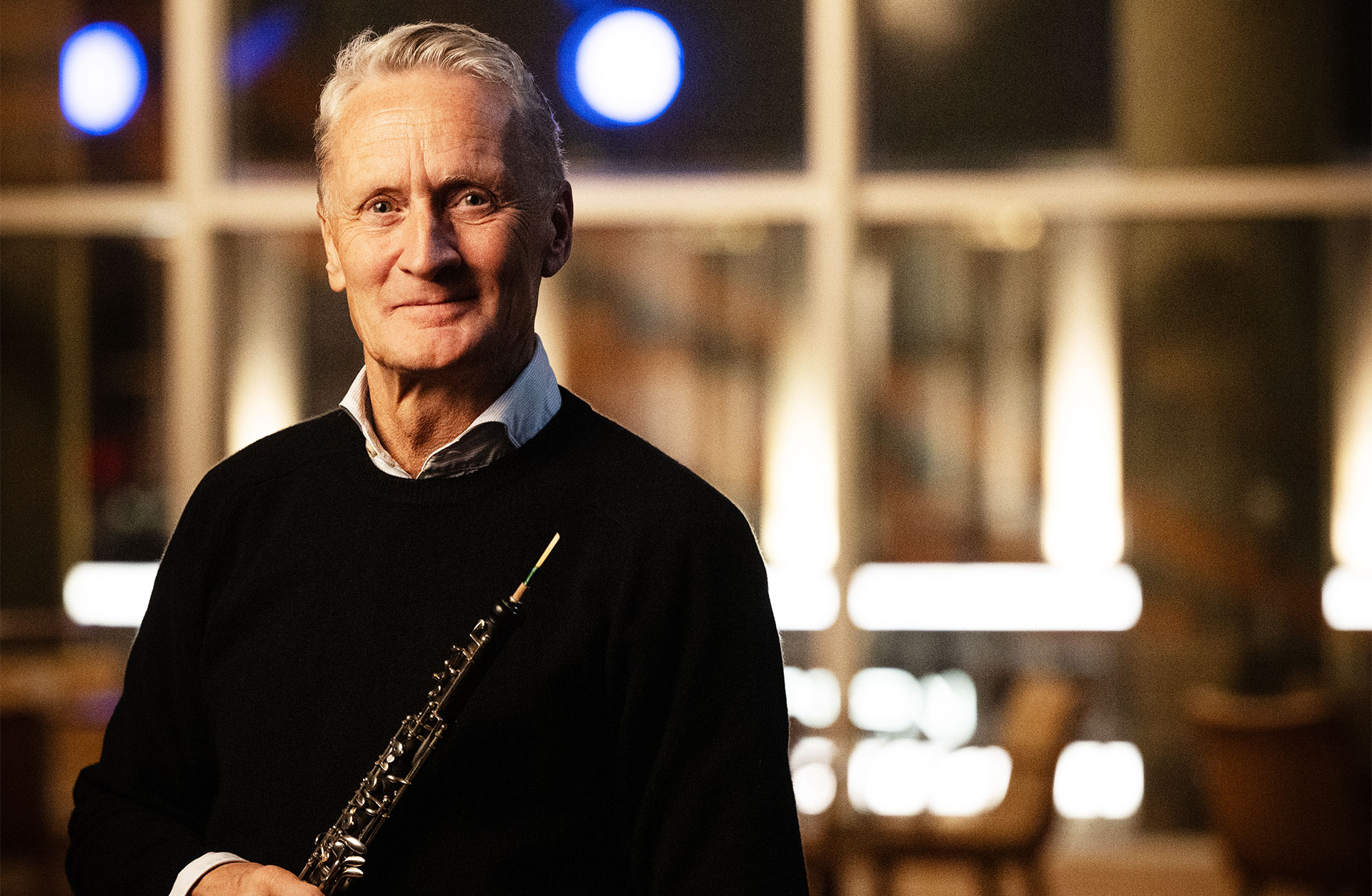 Mårten Larsson, en kortklippt man i 60-årsåldern tittar in i kameran och håller sin oboe.