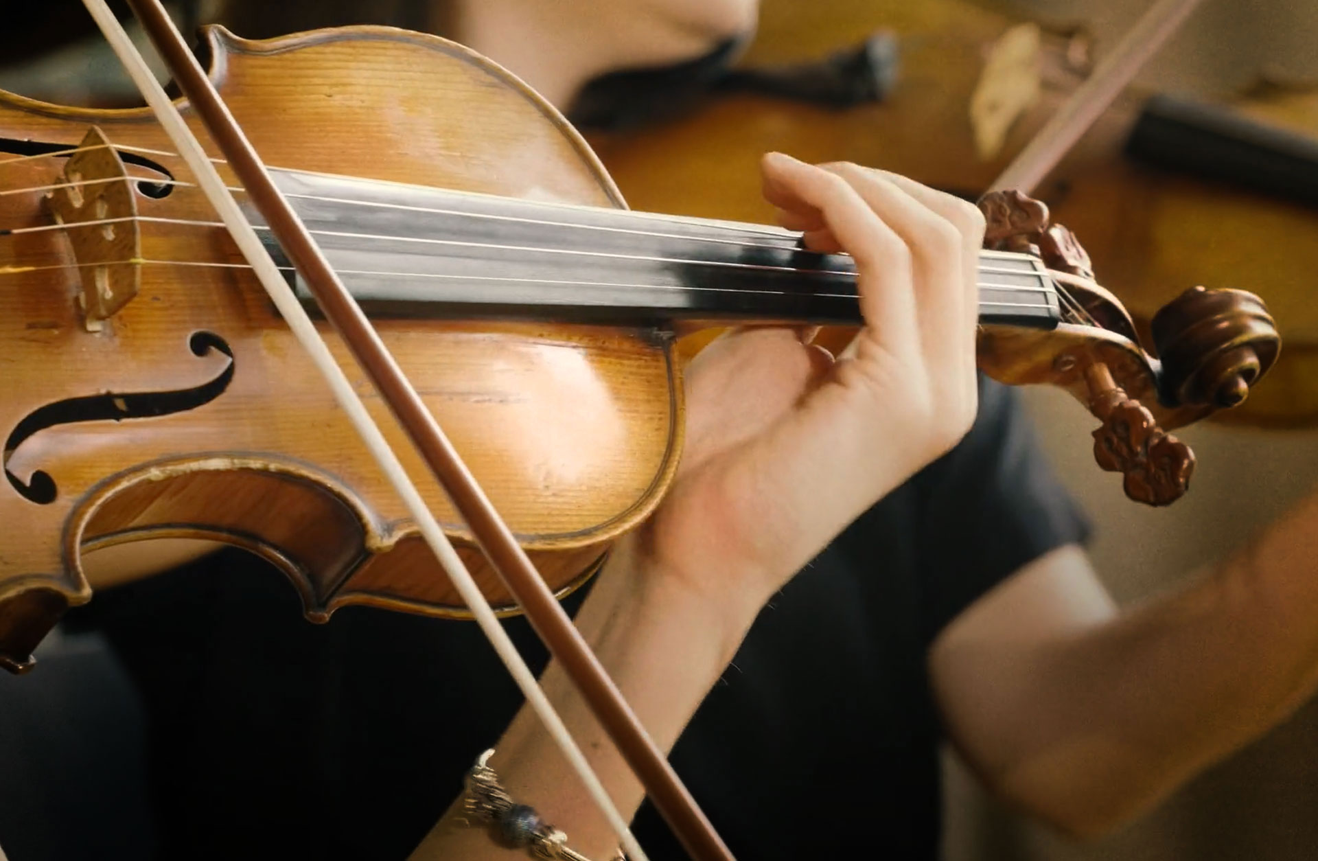 Närbild av en violin och en hand som spelar på strängarna.