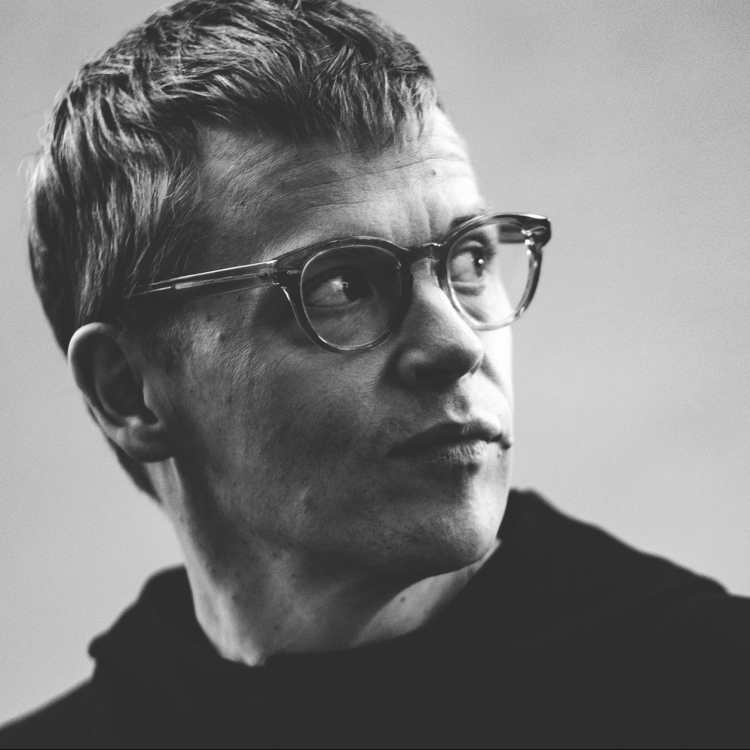 Svartvit bild av Pekka Kuusito. Det är en ansiktsbild och han vänder huvudet åt sidan.
