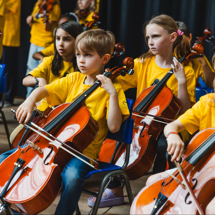 Barn i gula tröjor spelar cello.