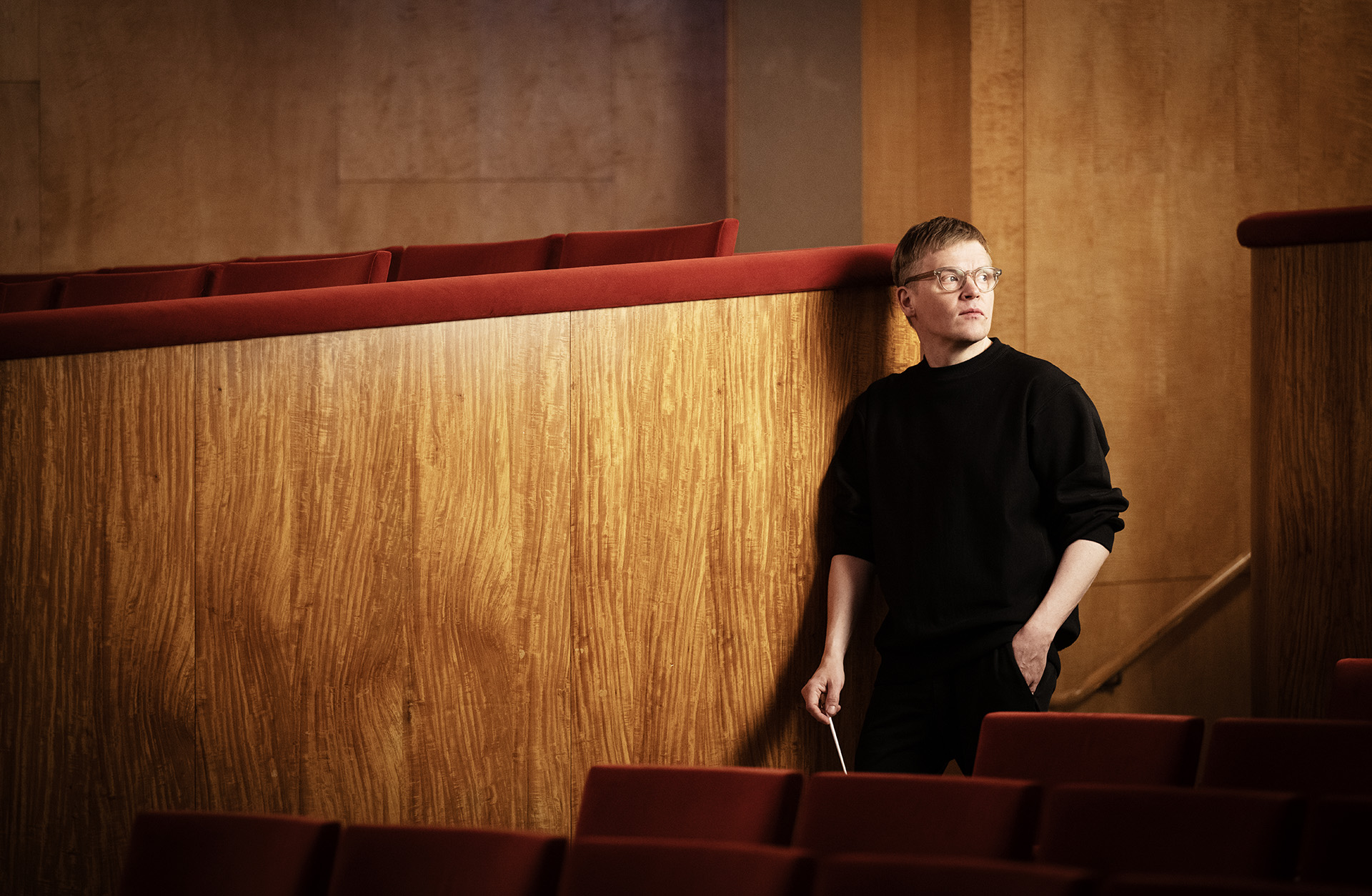 Pekka Kuusisto står lutad mot en vägg i trä