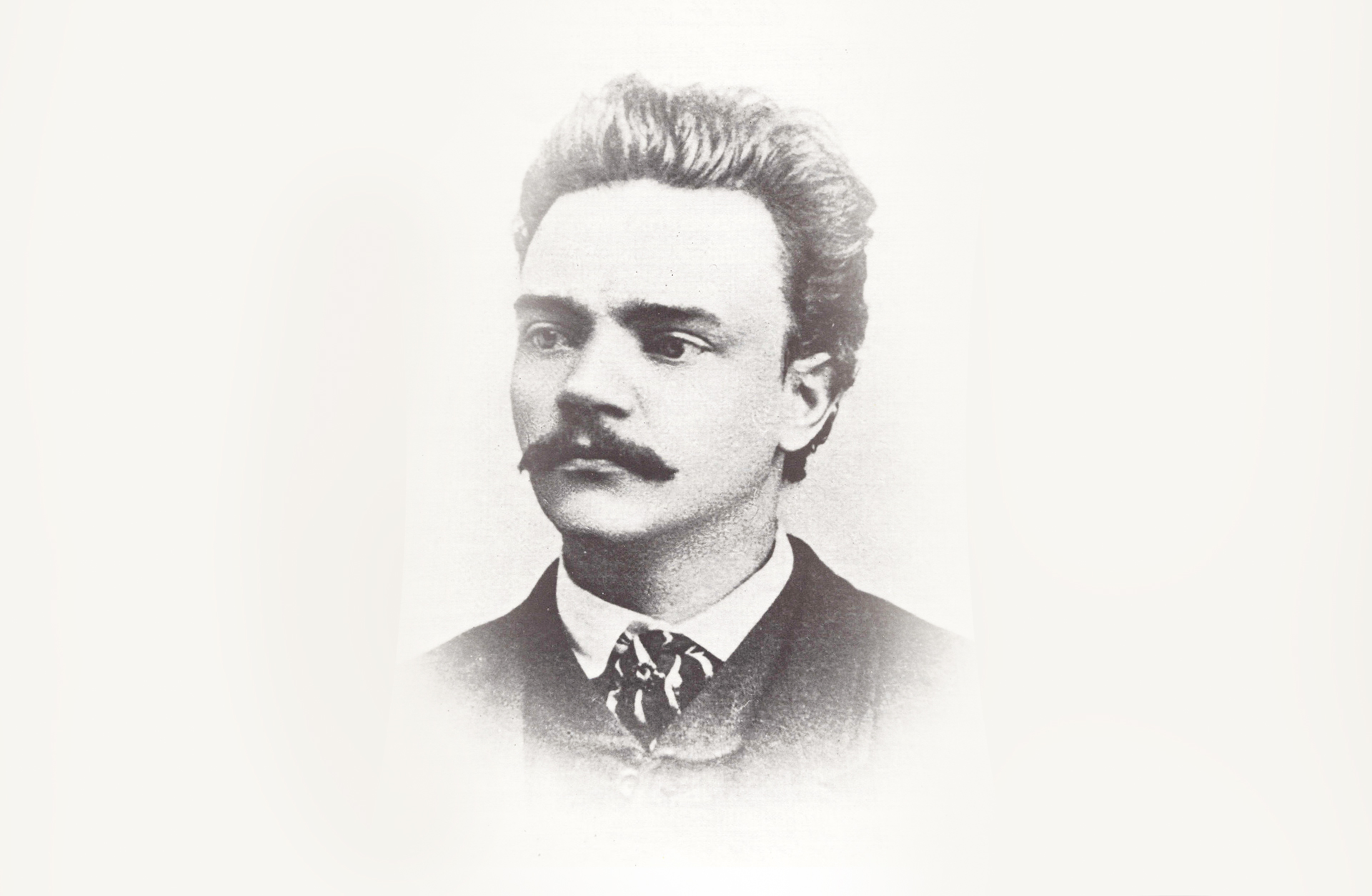 Ett svartvitt porträtt av en ung man med mustasch.