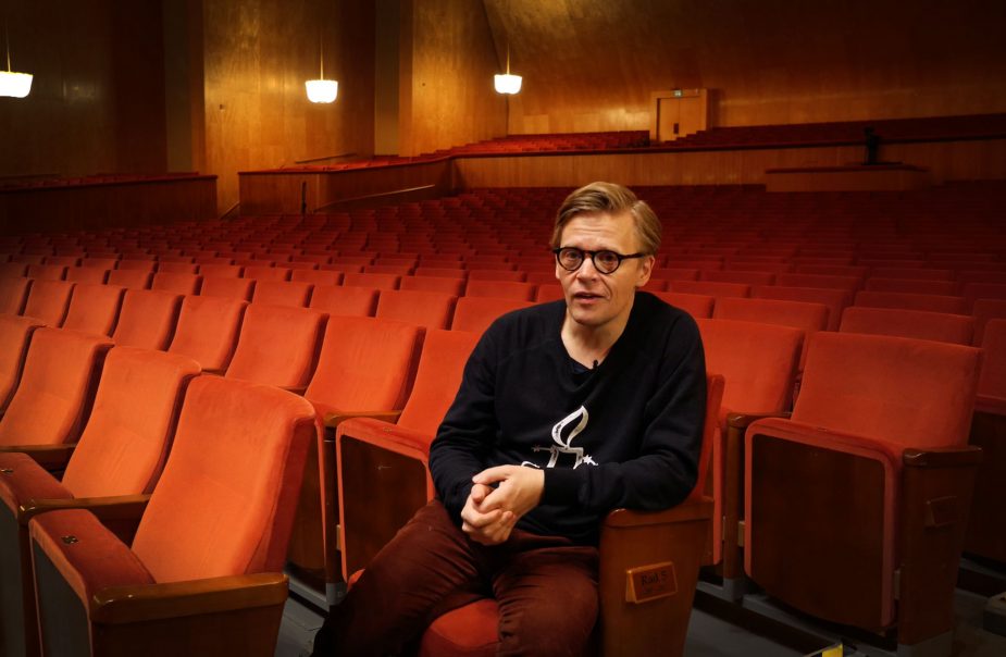 Pekka Kuusisto sitter i Stora salens röda stolar och pratar med ansiktet riktat mot kameran.