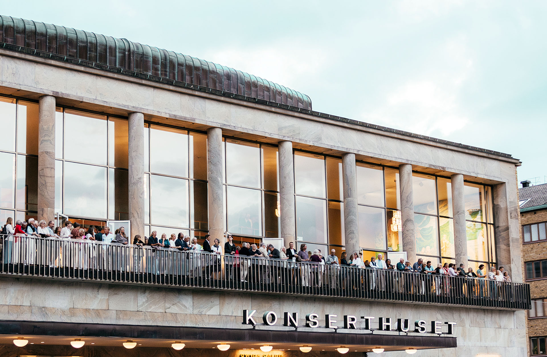 Vy över balkongen på konserthuset, full av minglande människor.