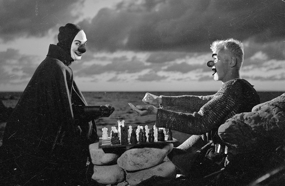 Två clowner spelar schack vid havet
